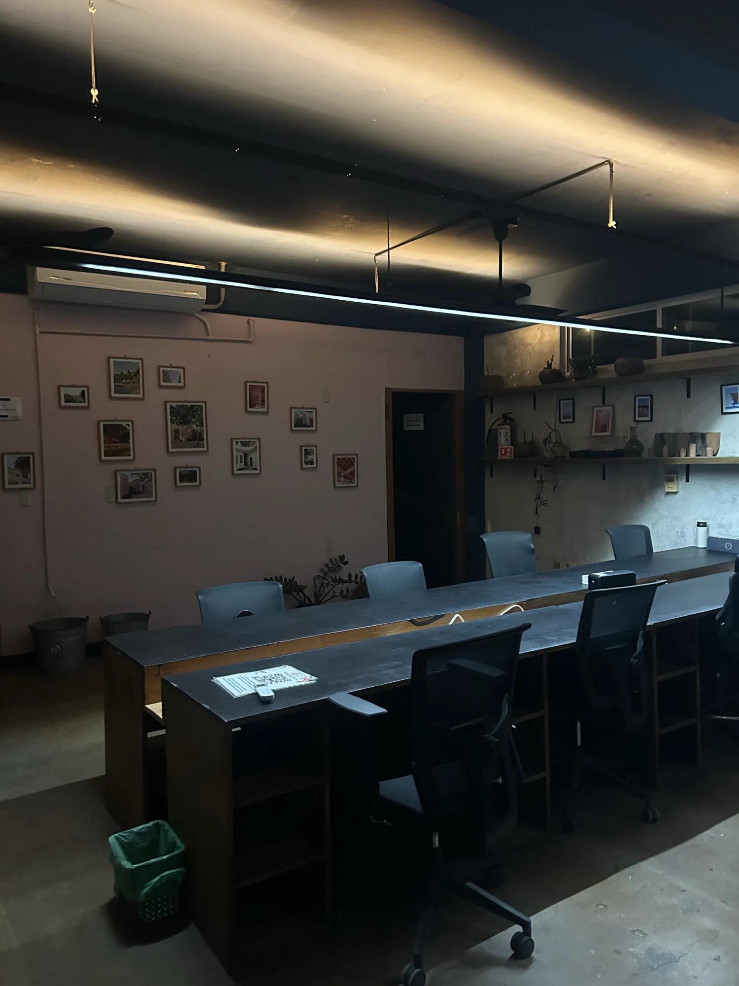 Interior de una oficina con una mesa larga de trabajo, sillas y luces en el techo