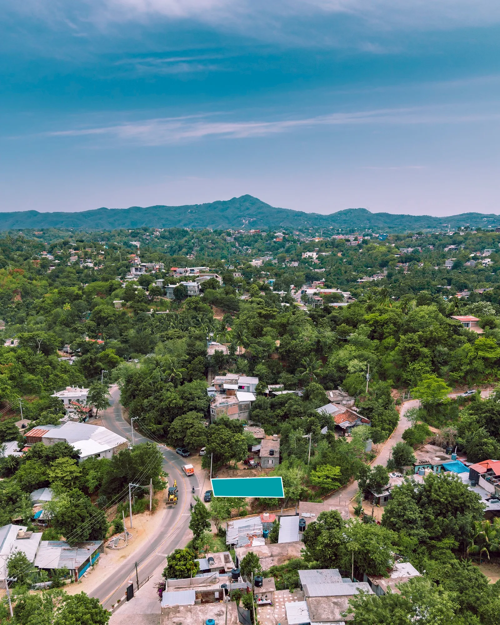 Vista aérea de un terreno marcado en verde azulado junto a una calle