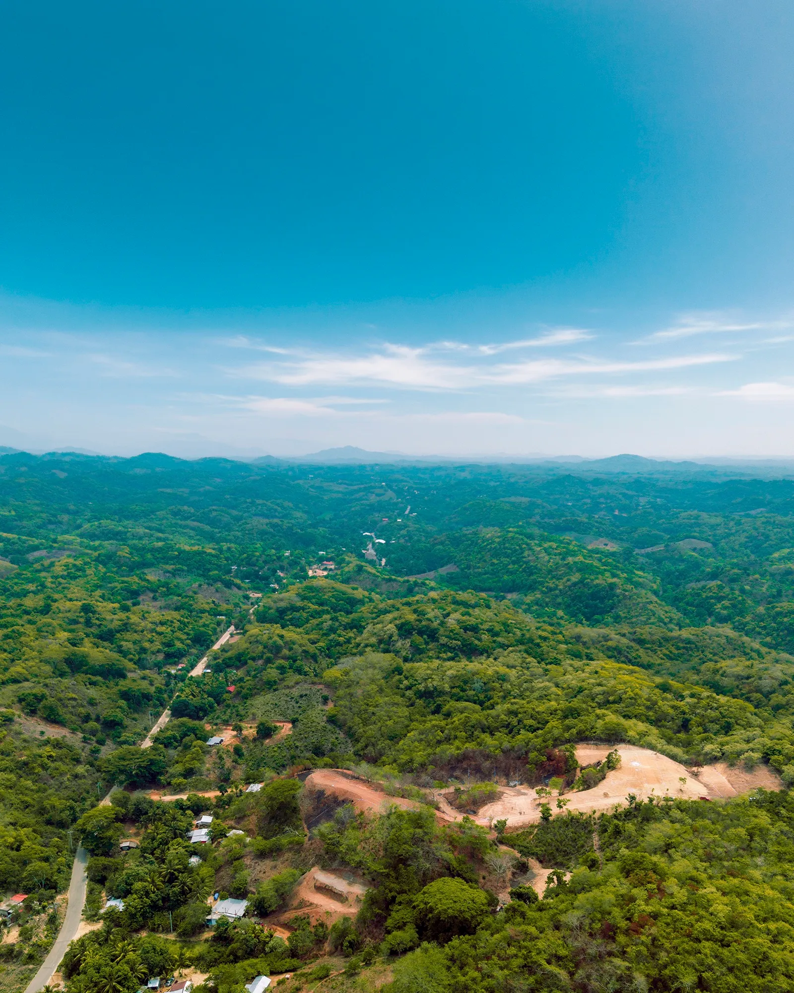 Vista aérea de lomas con vegetación y un claro de tierra entre los cerros