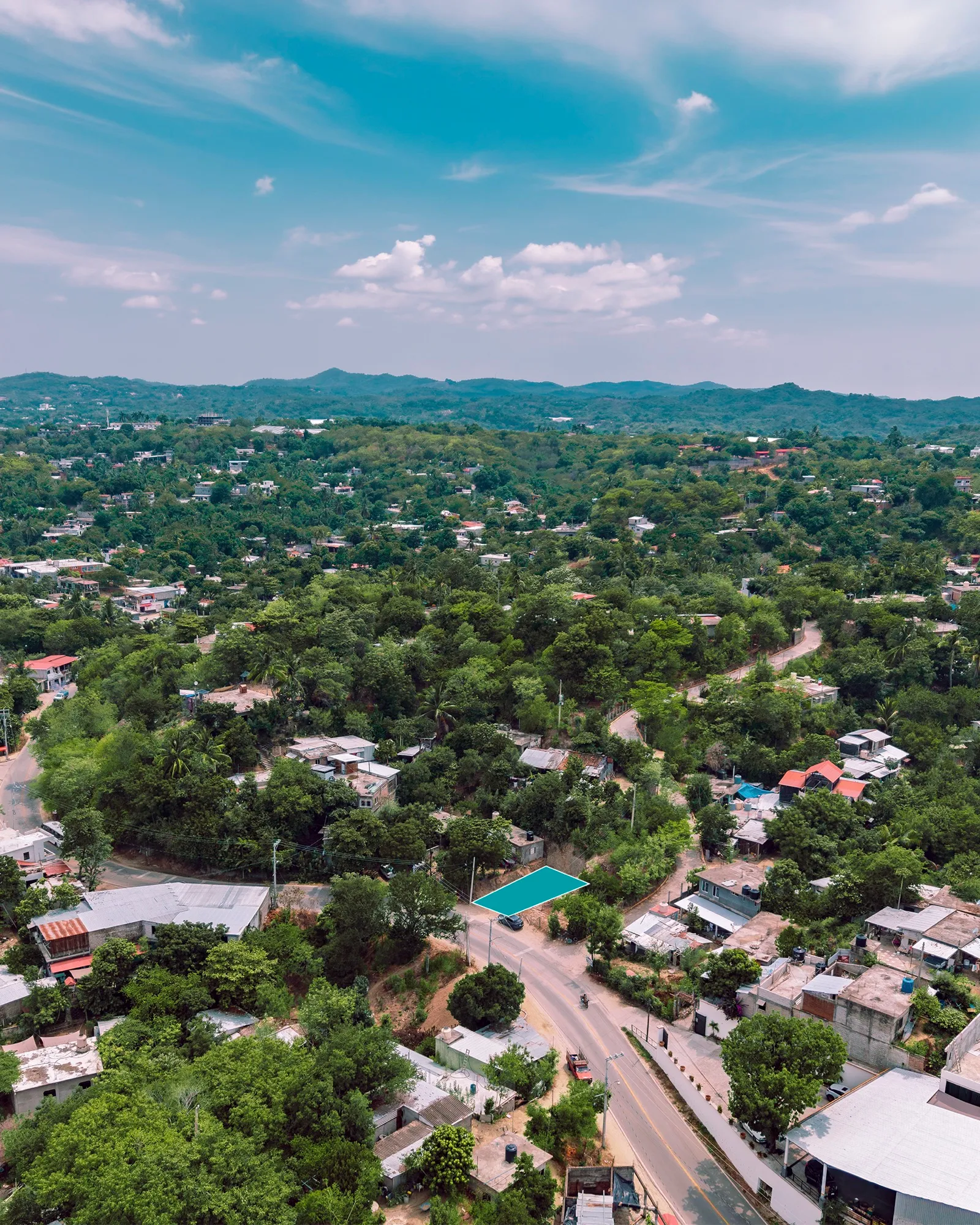 Vista aérea de un terreno marcado junto a una avenida entre casas y árboles