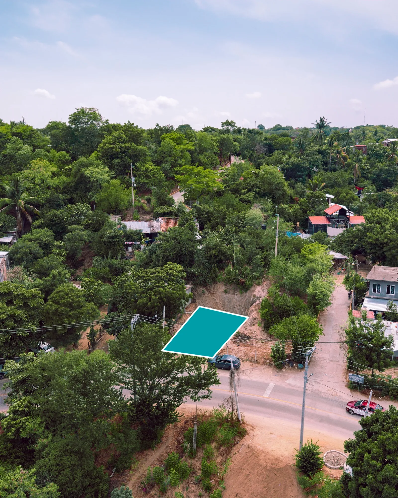 Vista aérea de un terreno marcado entre árboles junto a una calle