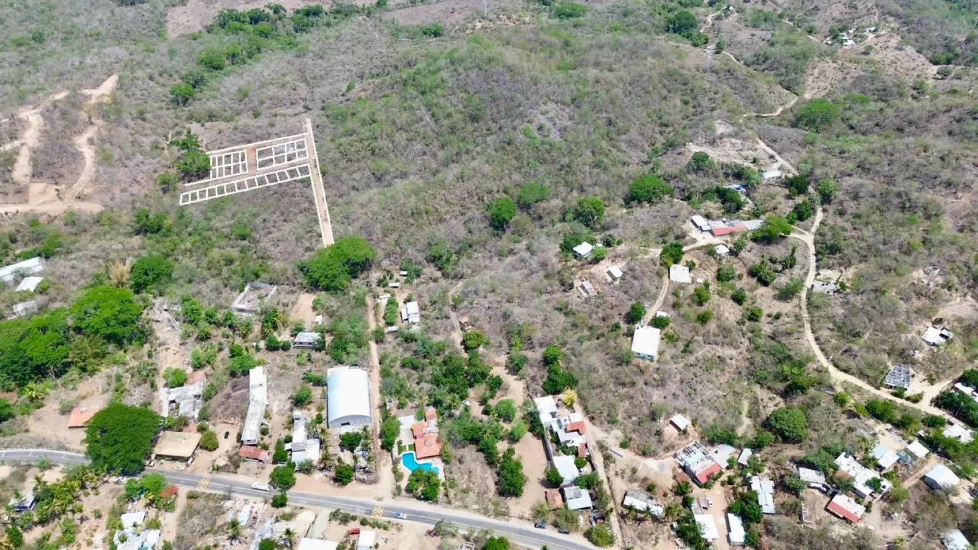 Vista aérea de un terreno con líneas blancas cerca de casas y una calle