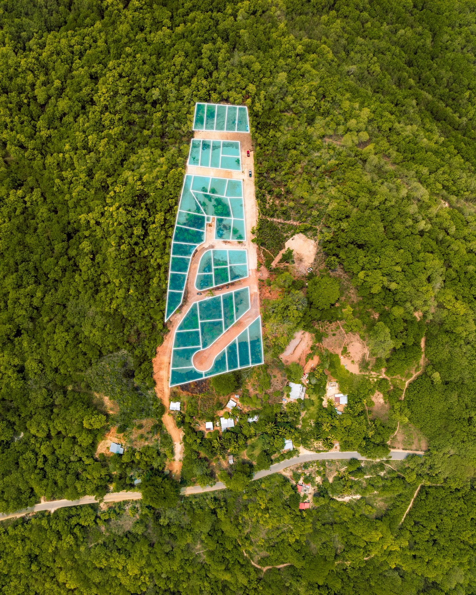 Vista desde arriba de lotes marcados en verde azulado en un terreno rodeado de vegetación