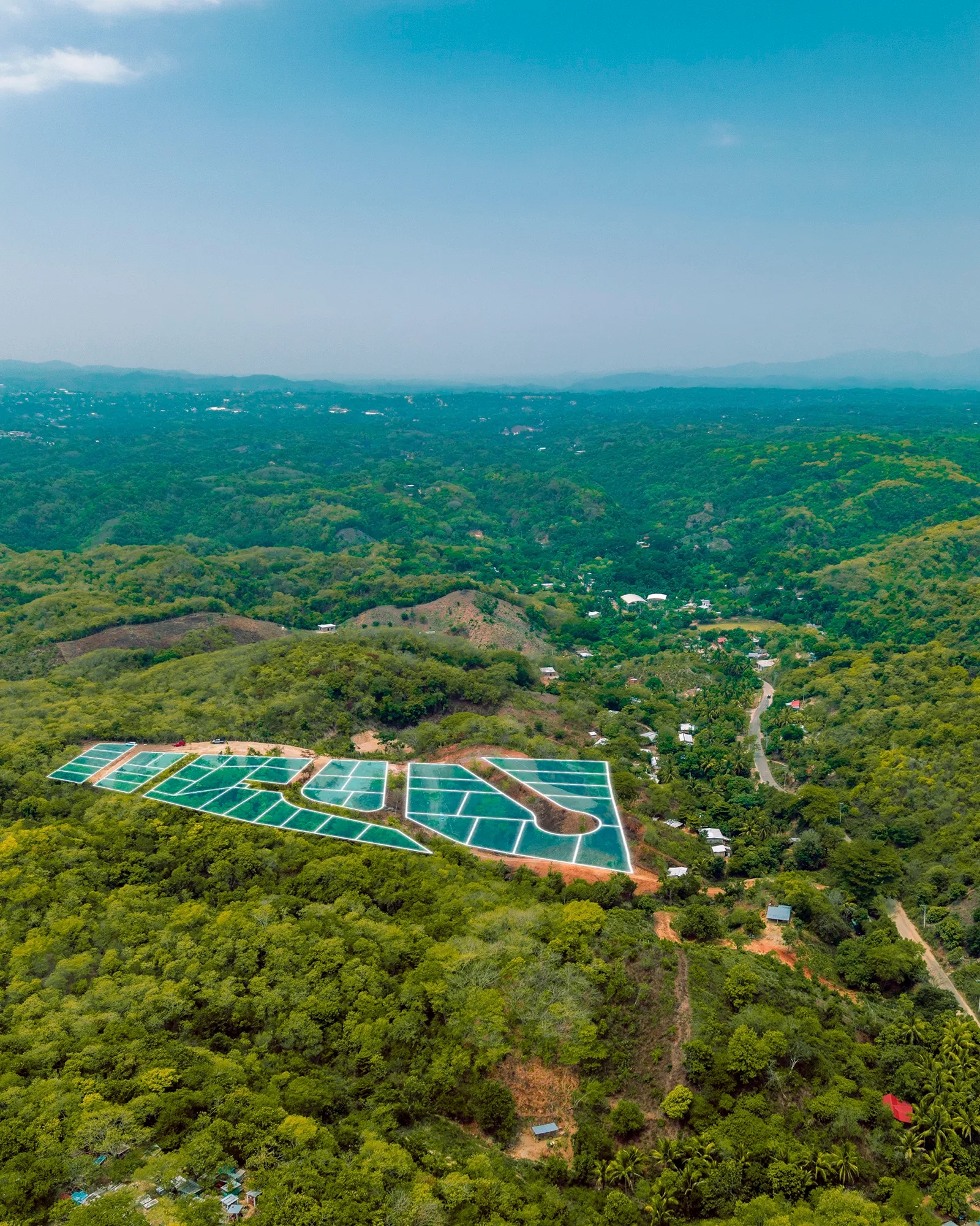 Vista aérea de lotes marcados en verde azulado sobre una loma con vegetación